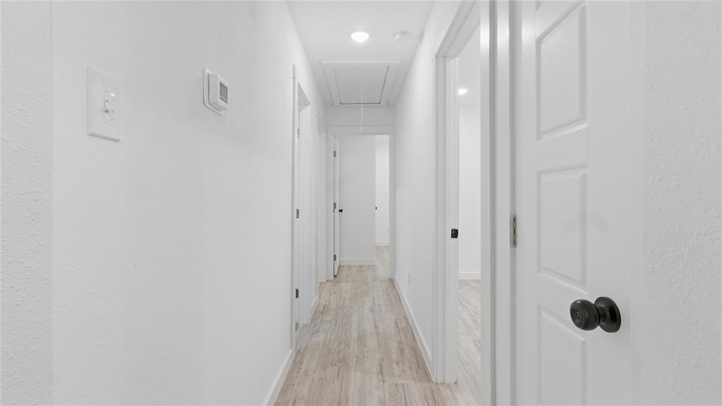 Hallway featuring wood-finish flooring, recessed lighting, and multi-panel interior doors with matte black hardware