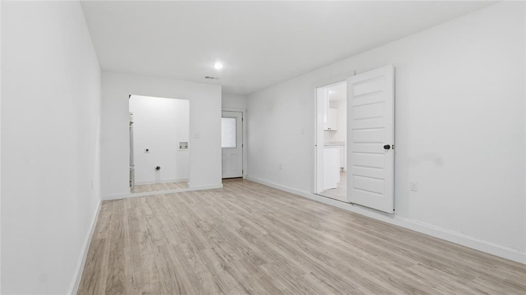 Neutral interior featuring wood-finish flooring, a multi-panel door, and recessed lighting