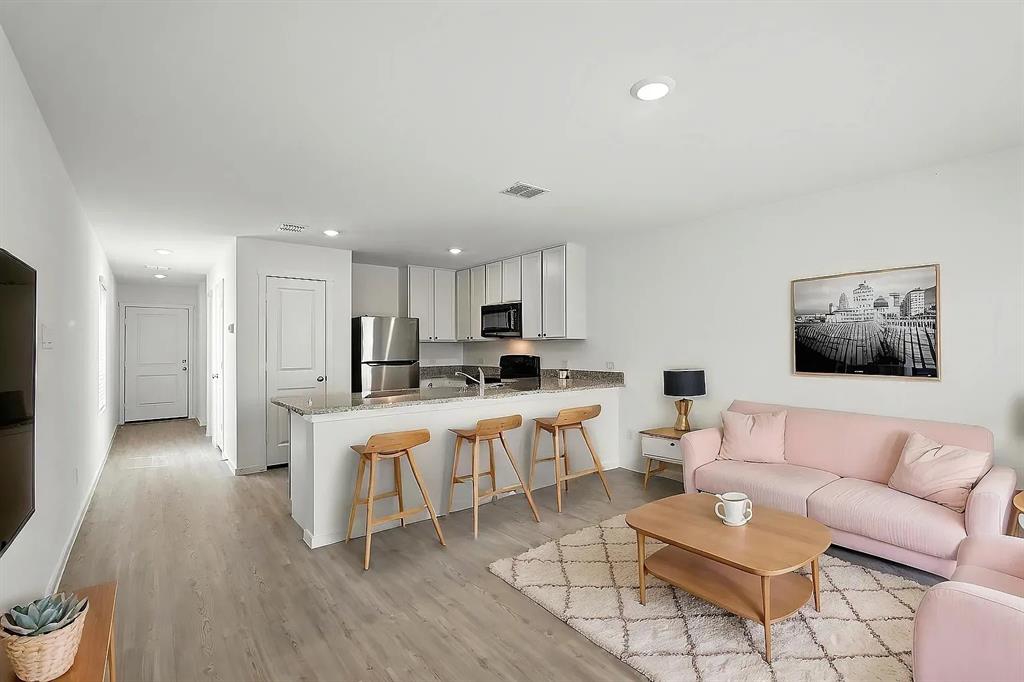 Kitchen featuring white cabinetry, stone-finish countertops, stainless steel appliances, and wood-finish flooring