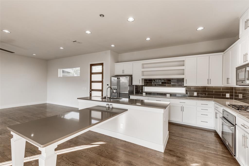 Kitchen featuring white shaker cabinetry, solid-surface countertops, extended breakfast bar, dark tiled backsplash, and wood-finish flooring