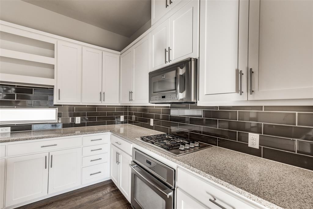 Kitchen featuring white cabinetry, stone-finish countertops, subway tile backsplash, built-in stainless steel microwave, and gas cooktop