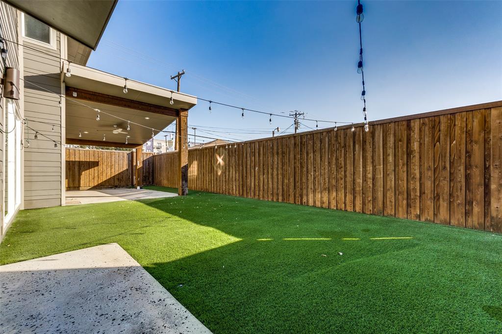 Backyard featuring a covered patio with a ceiling fan, synthetic turf lawn, and a privacy wood fence