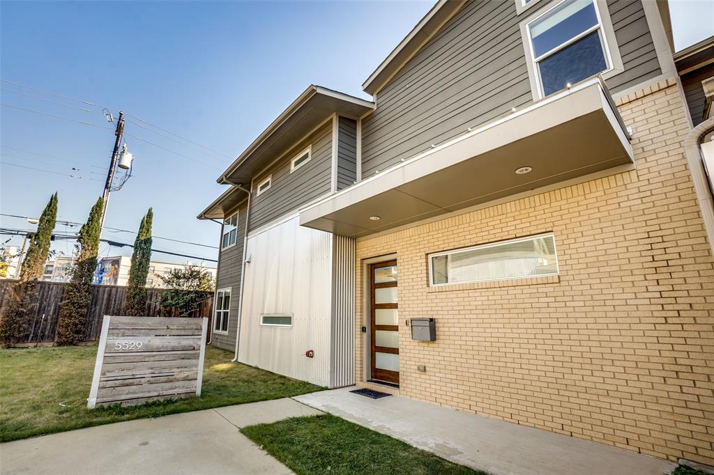 Modern exterior featuring a combination of brick, corrugated metal siding, and horizontal lap siding, complemented by a contemporary multi-panel wood door with frosted glass inserts and a cantilevered metal awning Modern exterior featuring a combination of brick, corrugated metal siding, and horizontal lap siding, complemented by a contemporary multi-panel wood door with frosted glass inserts and a cantilevered metal awning