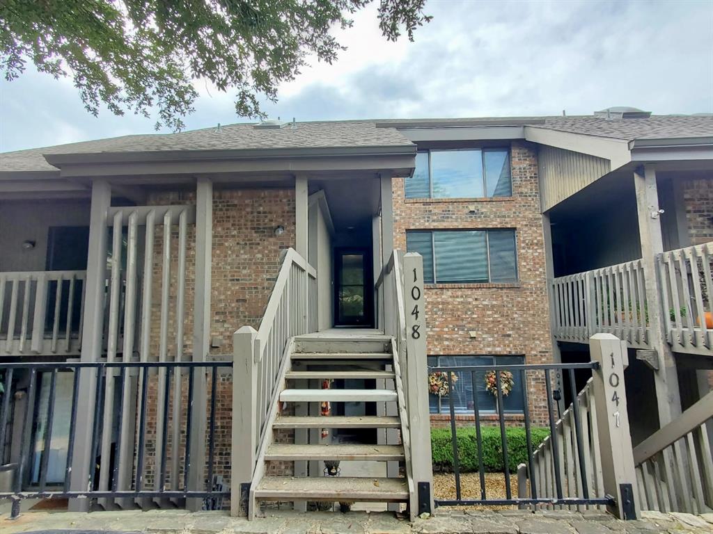 Multi-level exterior featuring brick masonry, timber-style accents, private staircases with railings, and neutral-toned shingle roofing Multi-level exterior featuring brick masonry, timber-style accents, private staircases with railings, and neutral-toned shingle roofing
