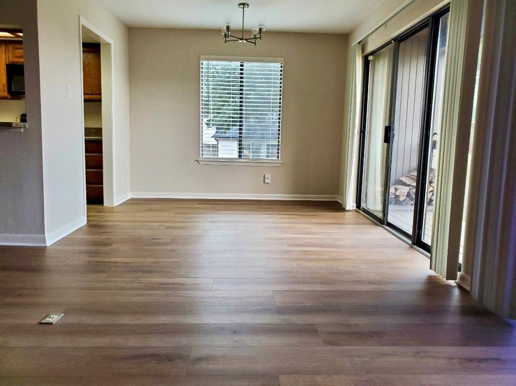 Wood-finish flooring, sliding glass patio door, multi-arm chandelier, and neutral wall color