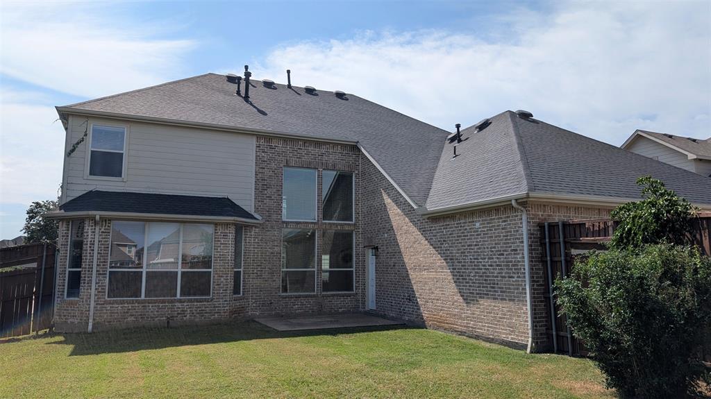 Exterior rear elevation featuring brick and horizontal siding, asphalt shingle roof, two-story window configurations, and a concrete patio