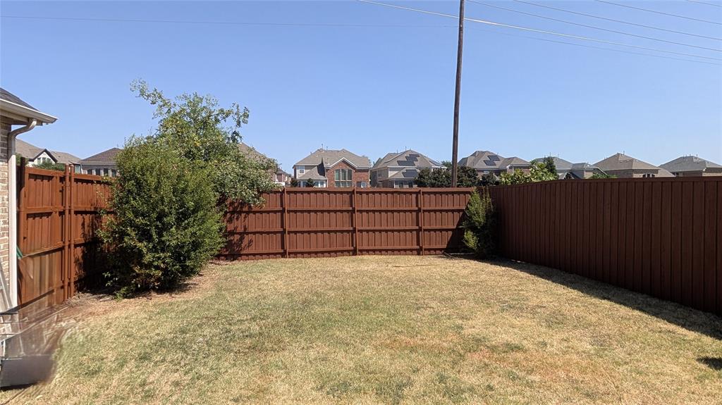 Rear yard featuring a grass lawn and full-height wood fencing