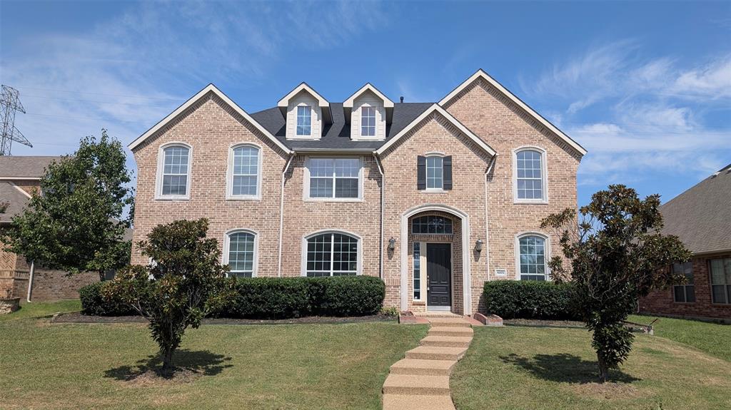 Multi-level brick exterior featuring dual gabled dormers, a prominent arched entryway, and multi-pane windows