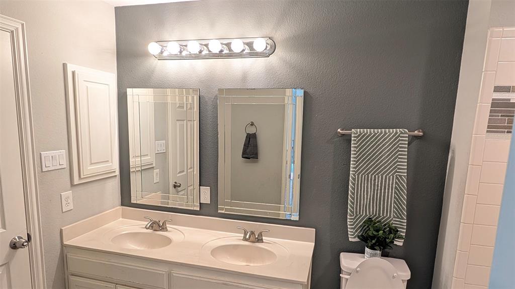 Double-sink vanity with a solid-surface countertop, dual rectangular mirrors with beveled edges, and six-bulb vanity lighting