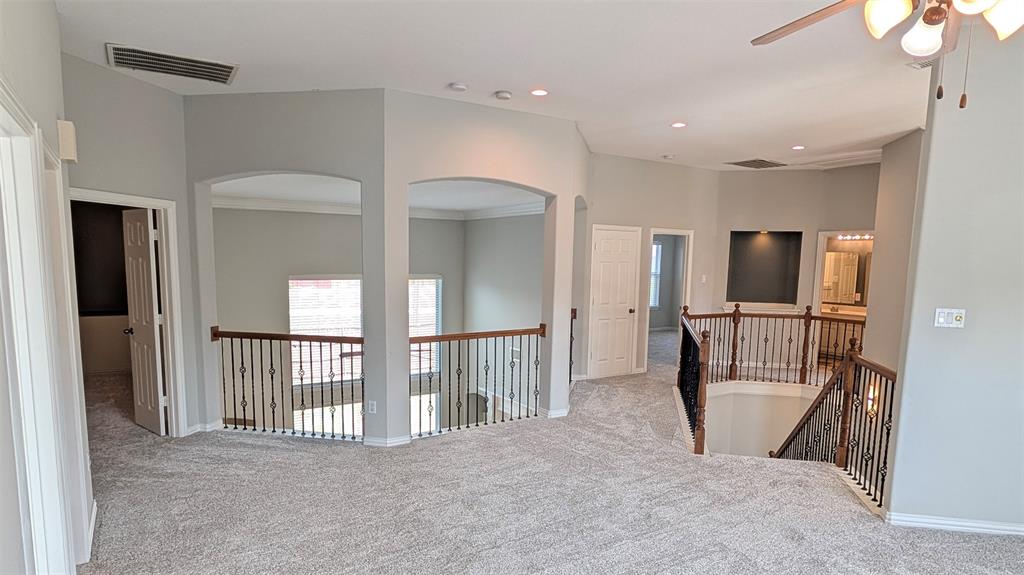 Open loft area featuring vaulted ceilings, recessed lighting, metal balusters with wooden handrails, arched architectural cutouts, and a built-in recessed niche