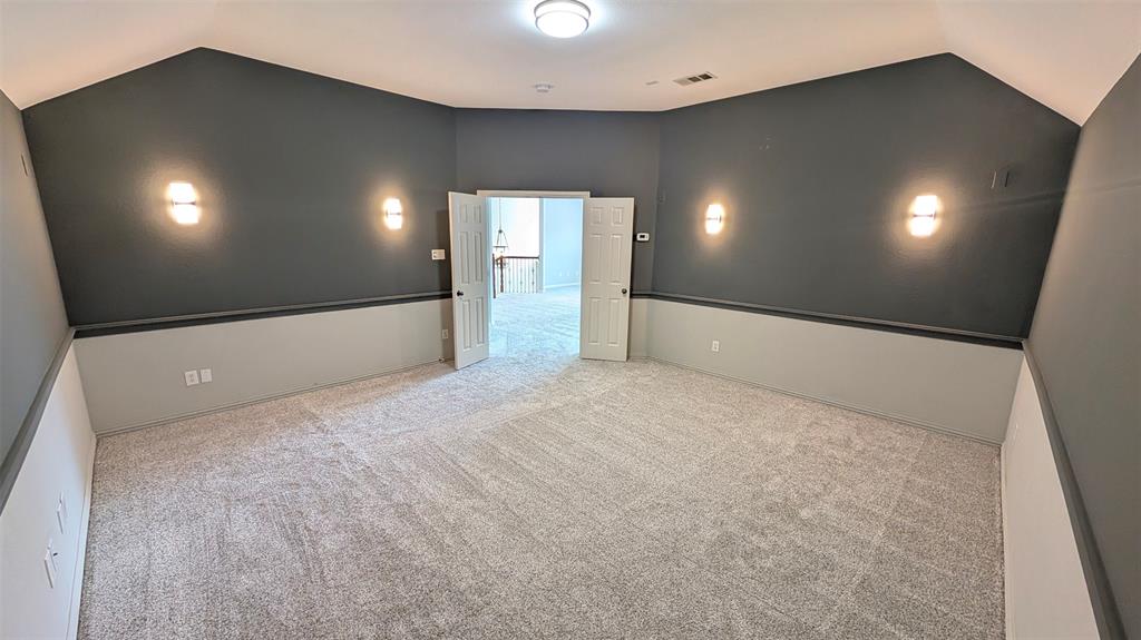 Vaulted ceiling, wall-to-wall carpeting, two-toned wall paint, decorative chair rail, and four wall-mounted sconces