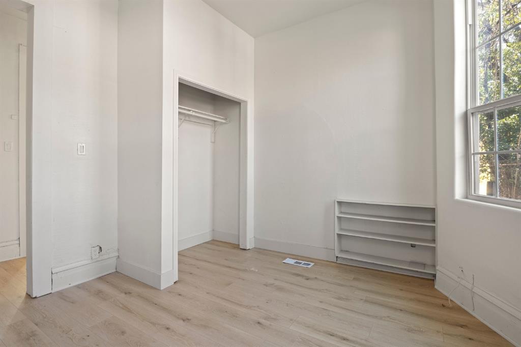 Interior space featuring wood-finish flooring, a built-in recessed storage shelf, a walk-in closet with integrated shelving, and a double-pane window