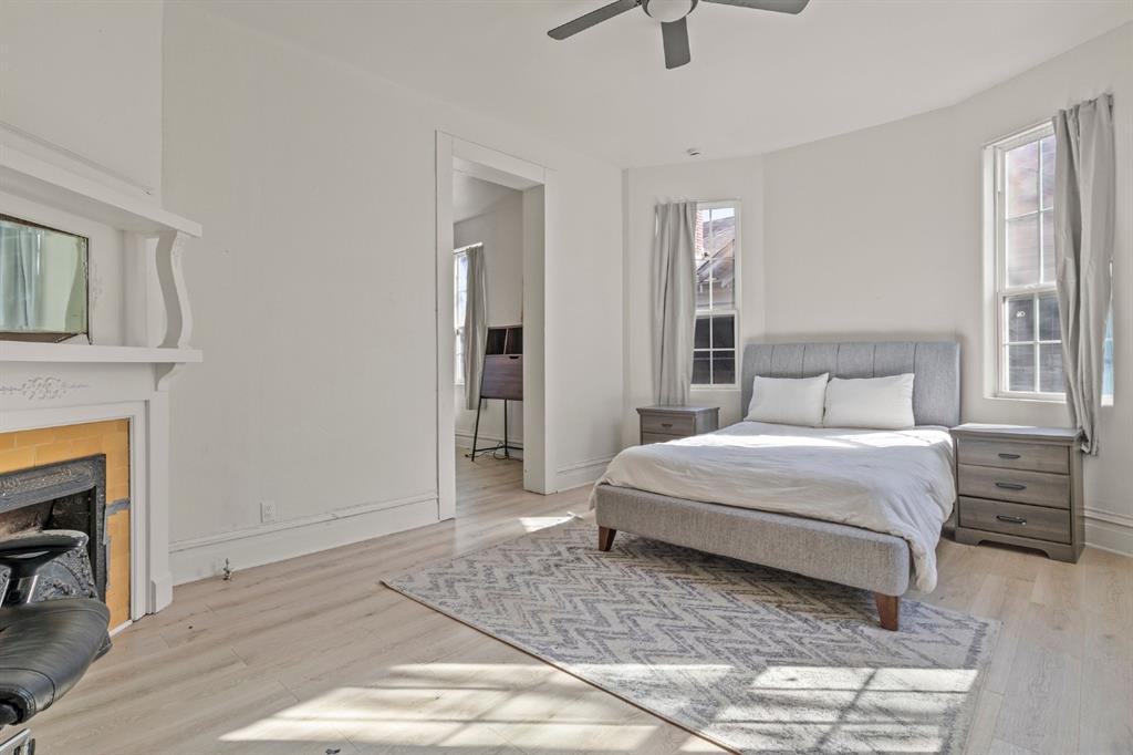 Decorative fireplace mantel, wood-finish flooring, bay-style window configuration, and ceiling-mounted fan Decorative fireplace mantel, wood-finish flooring, bay-style window configuration, and ceiling-mounted fan