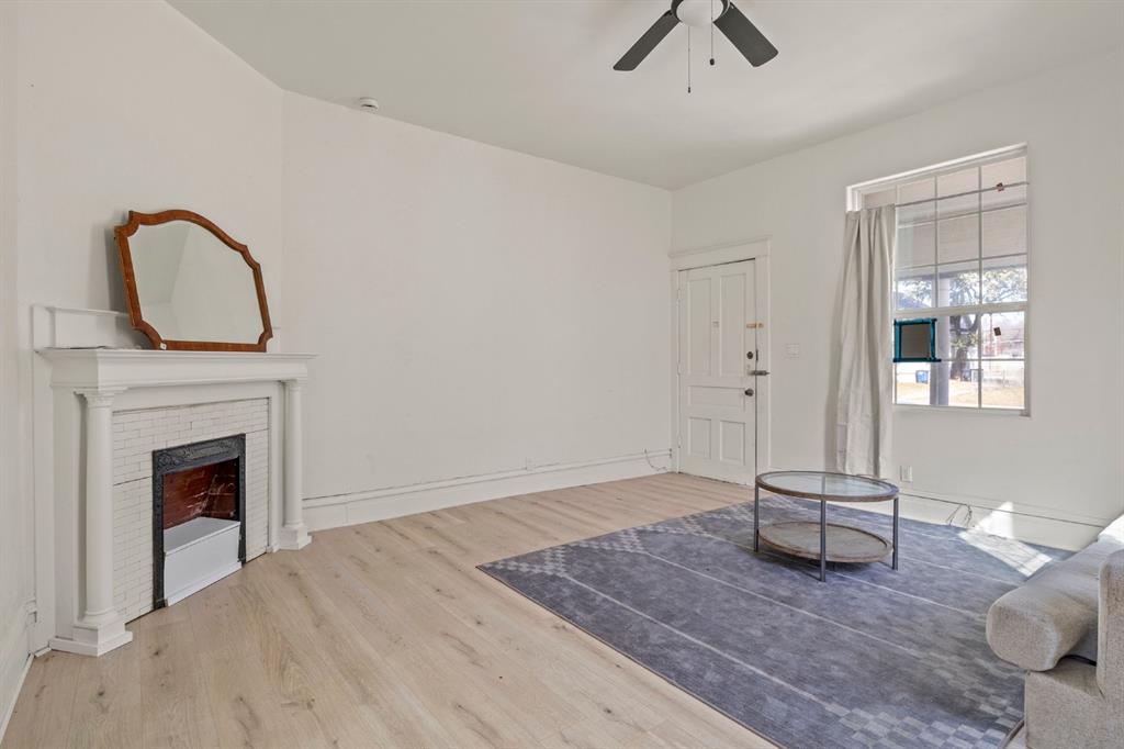 Living area featuring wood-finish flooring, a fireplace with a decorative mantel, and a multi-pane window
