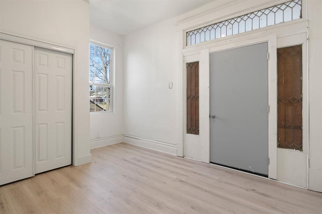 Interior space featuring wood-finish flooring, a multi-panel sliding closet, an exterior door with integrated leaded-glass sidelights, and a matching leaded-glass transom window