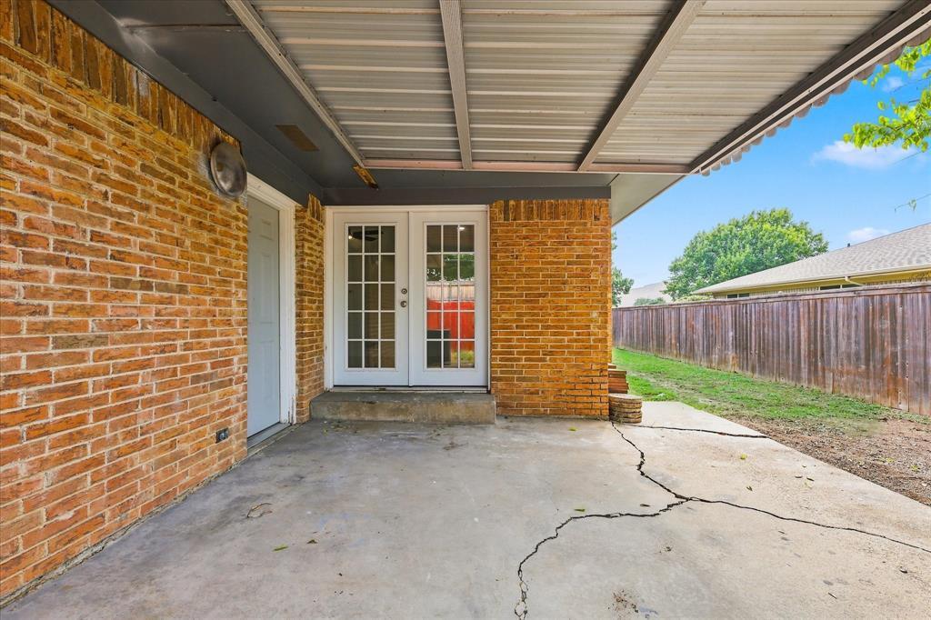 Covered concrete patio featuring brick exterior walls and glass paneled French doors