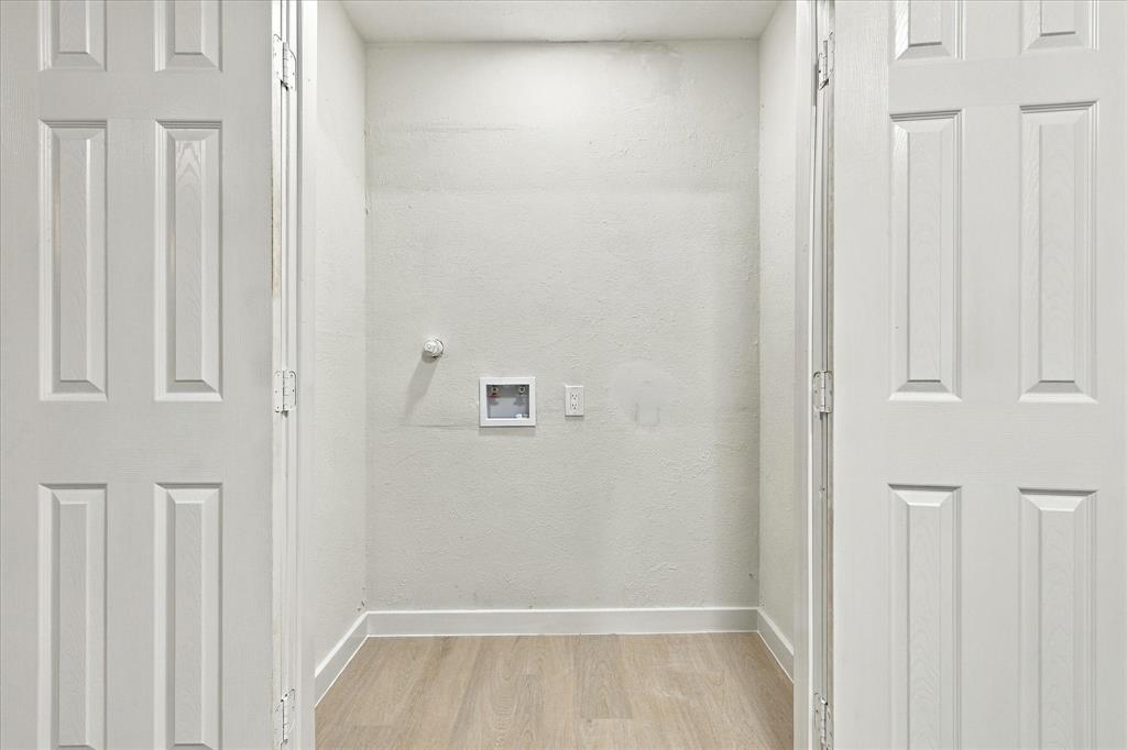 Dedicated utility alcove featuring dual-panel closet doors, wood-finish flooring, and recessed laundry hookups