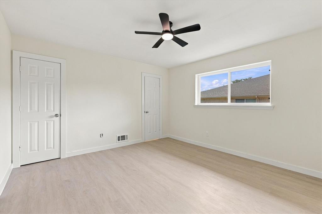 Interior room featuring wood-finish flooring, a ceiling fan with integrated lighting, a sliding window, and two paneled interior doors