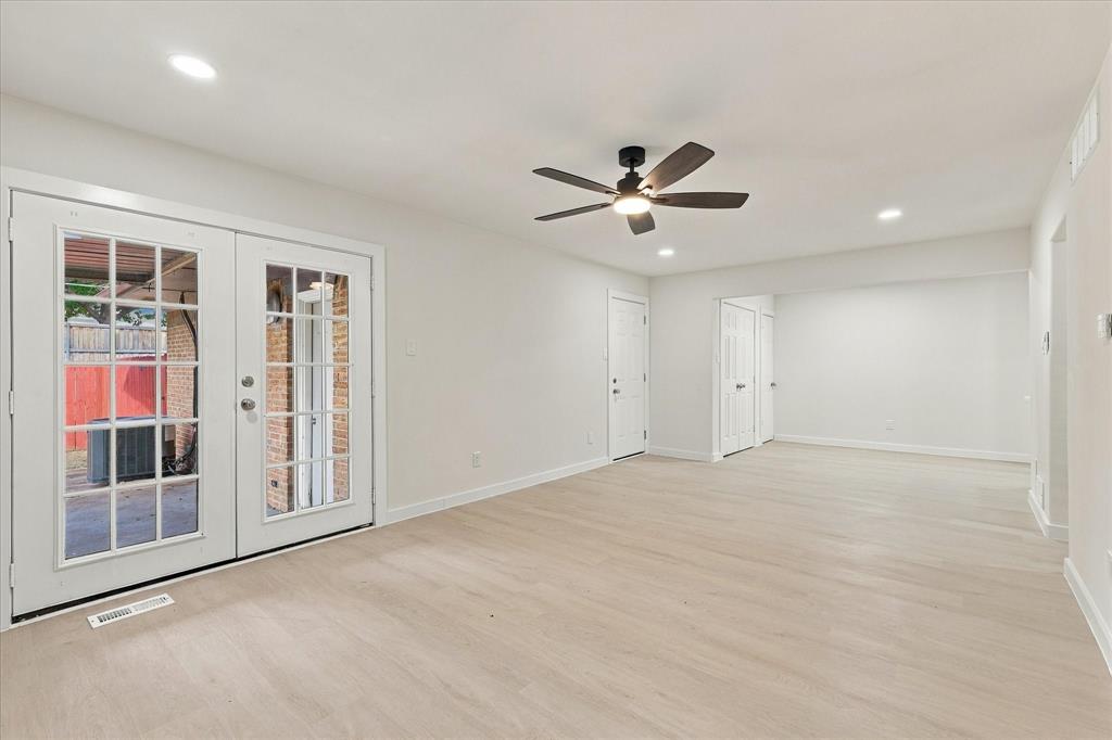 Interior featuring light-toned wood-finish flooring, recessed lighting, matte black ceiling fan, and white French doors with glass panes