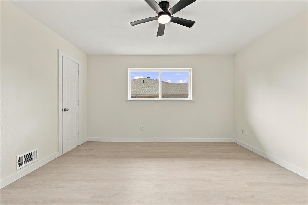 Neutral interior space featuring wood-finish flooring, a matte black ceiling fan with integrated lighting, and a single-hung window with white trim