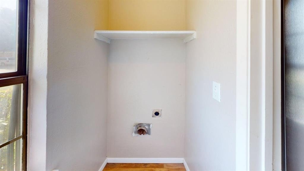 Dedicated utility alcove featuring wood-finish flooring, neutral wall paint, and built-in overhead shelving
