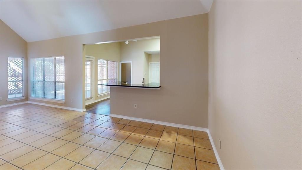 Vaulted ceilings, neutral wall tones, large windows, ceramic tile flooring, and a breakfast bar with a solid surface countertop