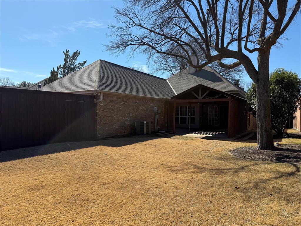 Backyard featuring a brick exterior, covered patio, wood fencing, and mature trees