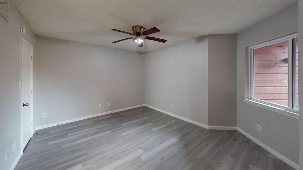 Room featuring wood-finish flooring, a neutral color palette, and an integrated ceiling fan with light fixture