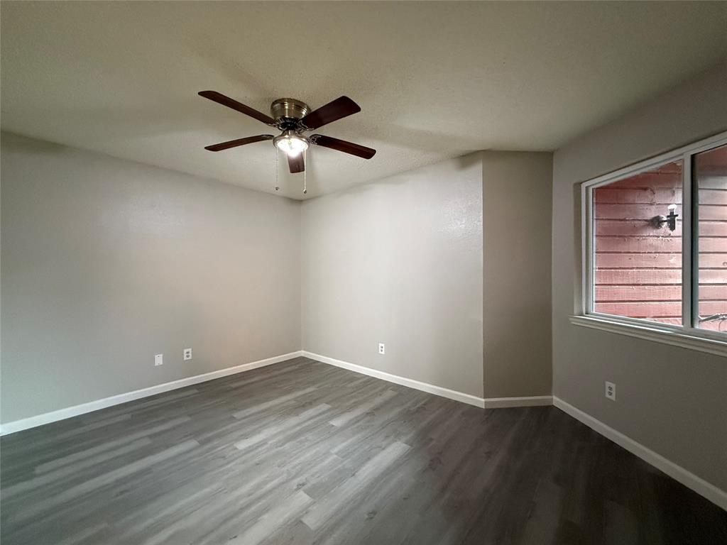 Room featuring wood-finish flooring, neutral wall paint, and a ceiling-mounted fan with integrated lighting