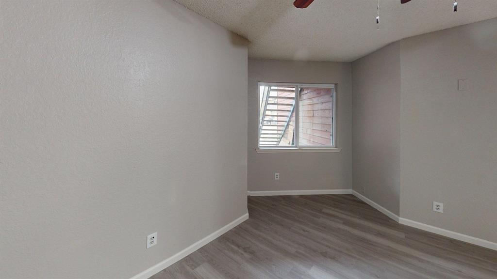 Interior space featuring neutral wall paint, wood-finish flooring, a sliding glass window, and an overhead ceiling fan