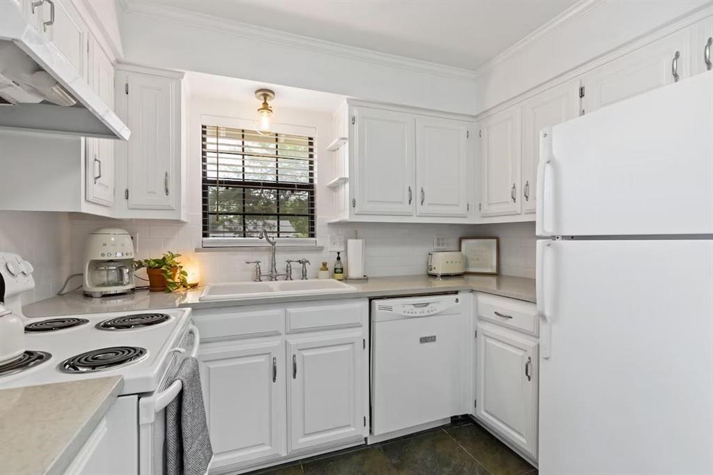 Kitchen featuring white cabinetry, solid surface countertops, a white double-basin sink with a gooseneck faucet, subway tile backsplash, and tile flooring