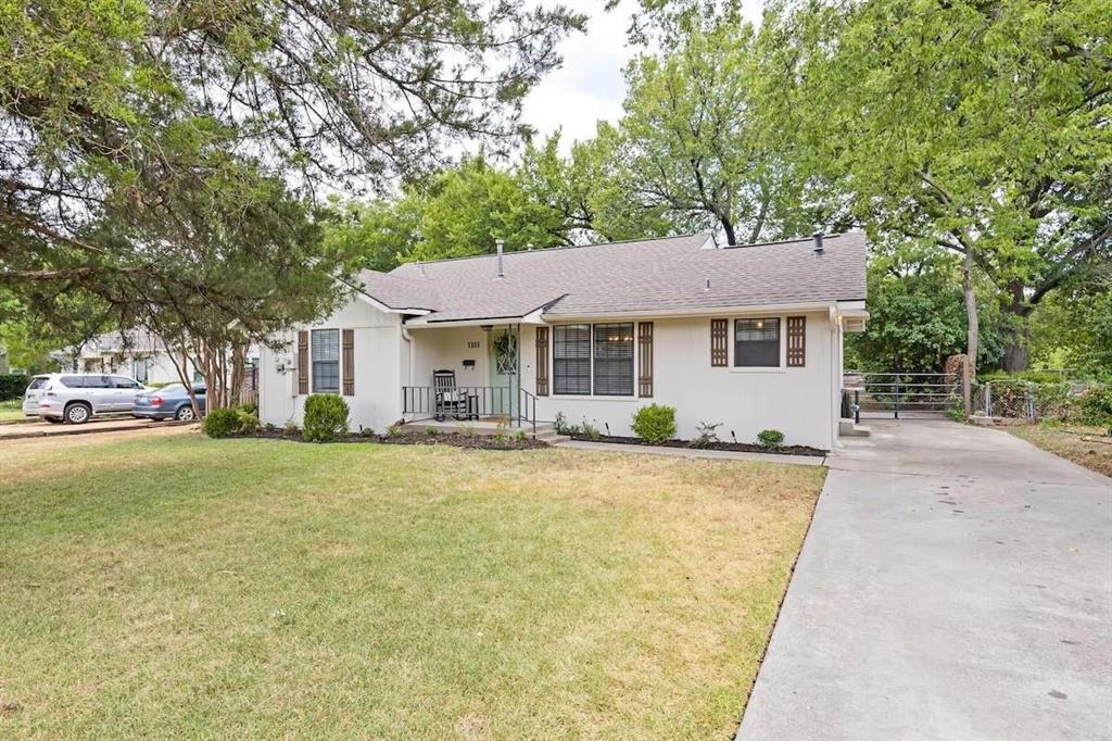 Single-story exterior featuring light-toned siding, decorative shutters, a concrete driveway, and mature landscaping Single-story exterior featuring light-toned siding, decorative shutters, a concrete driveway, and mature landscaping