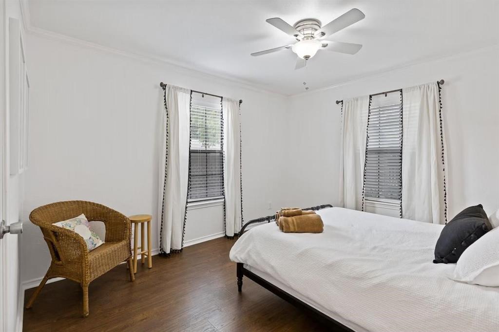 Bedroom featuring wood-finish flooring, dual windows with horizontal blinds, and a central ceiling fan with integrated lighting