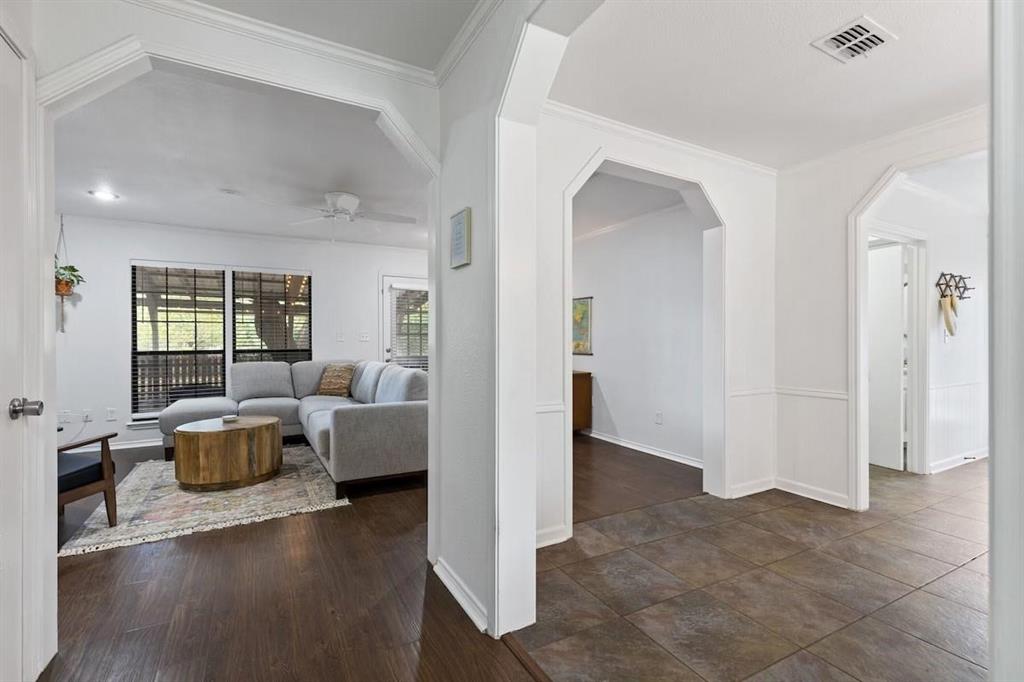 Interior featuring large architectural archways, dark wood-finish flooring, and earth-tone tile flooring with wainscoting Interior featuring large architectural archways, dark wood-finish flooring, and earth-tone tile flooring with wainscoting