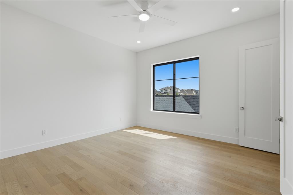 Spacious room featuring light wood-finish flooring and crisp white walls