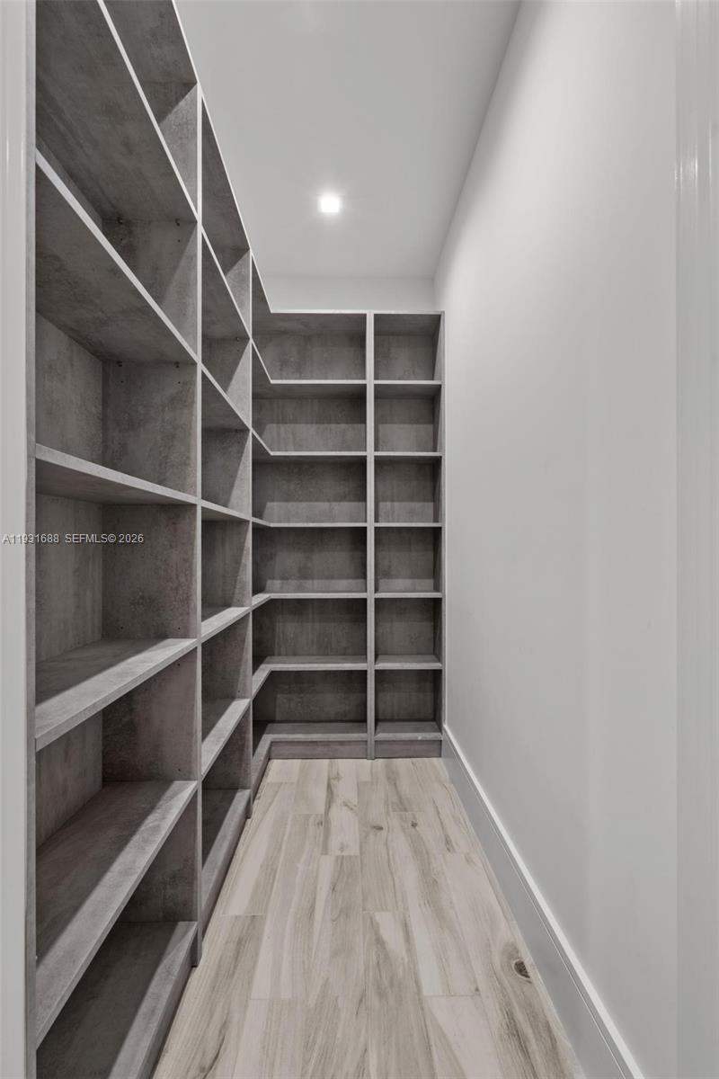 Floor-to-ceiling built-in shelving with a gray finish, recessed ceiling lighting, and wood-finish flooring
