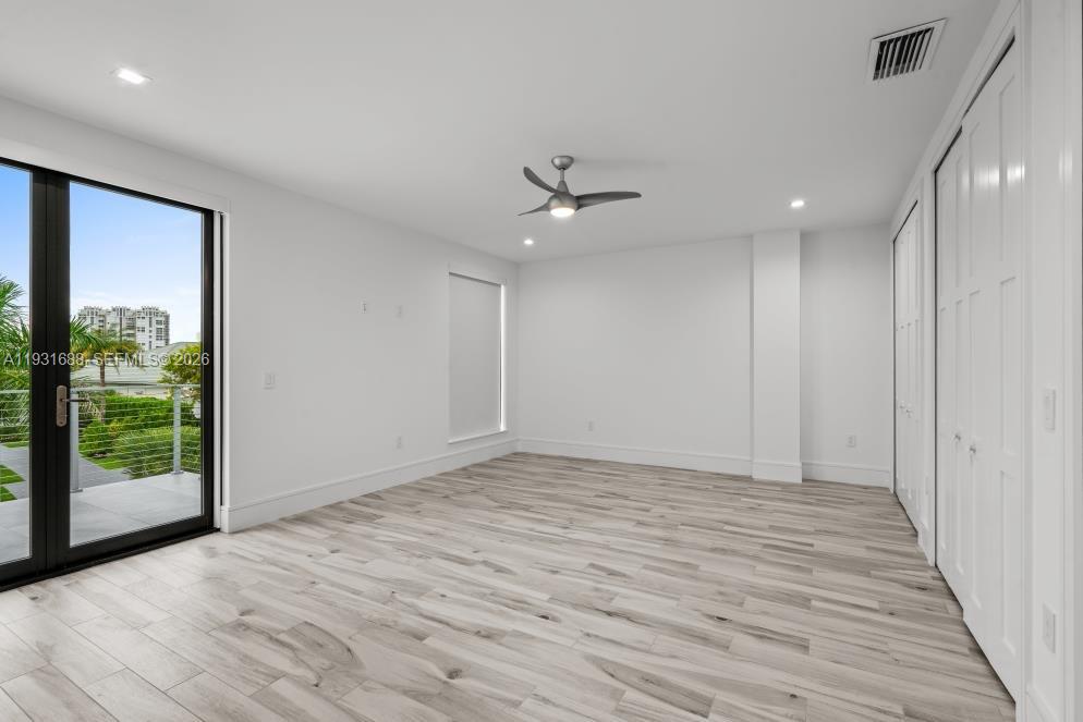 Interior space featuring wood-finish flooring, recessed lighting, a modern ceiling fan, floor-to-ceiling glass door, and white bi-fold closet doors