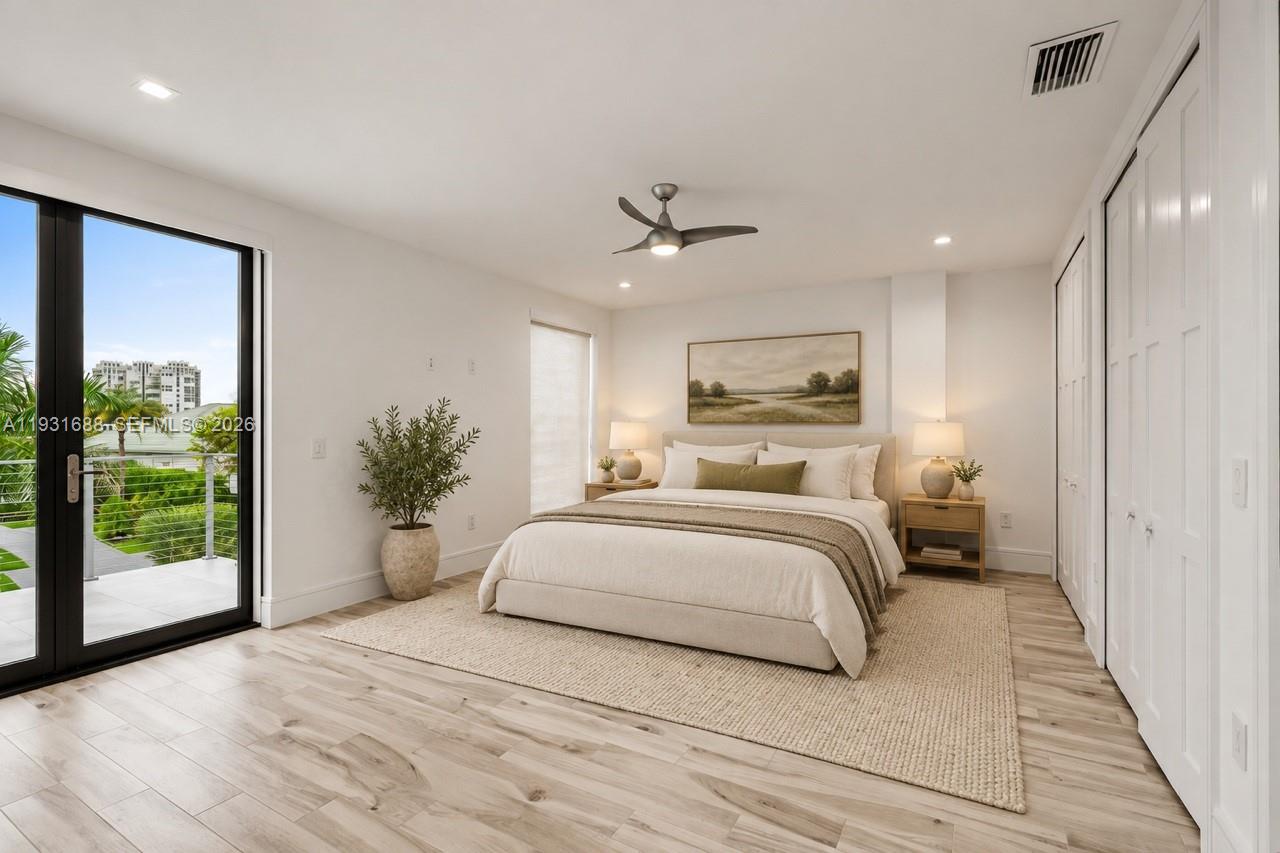 Wood-finish flooring, full-height glass door with black frame, recessed ceiling lighting, three-blade ceiling fan, and multi-panel floor-to-ceiling closet doors