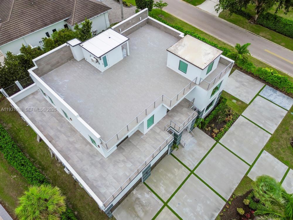 Contemporary exterior featuring a rooftop terrace with metal railings, expansive paved hardscaping, and a multi-level flat roof design