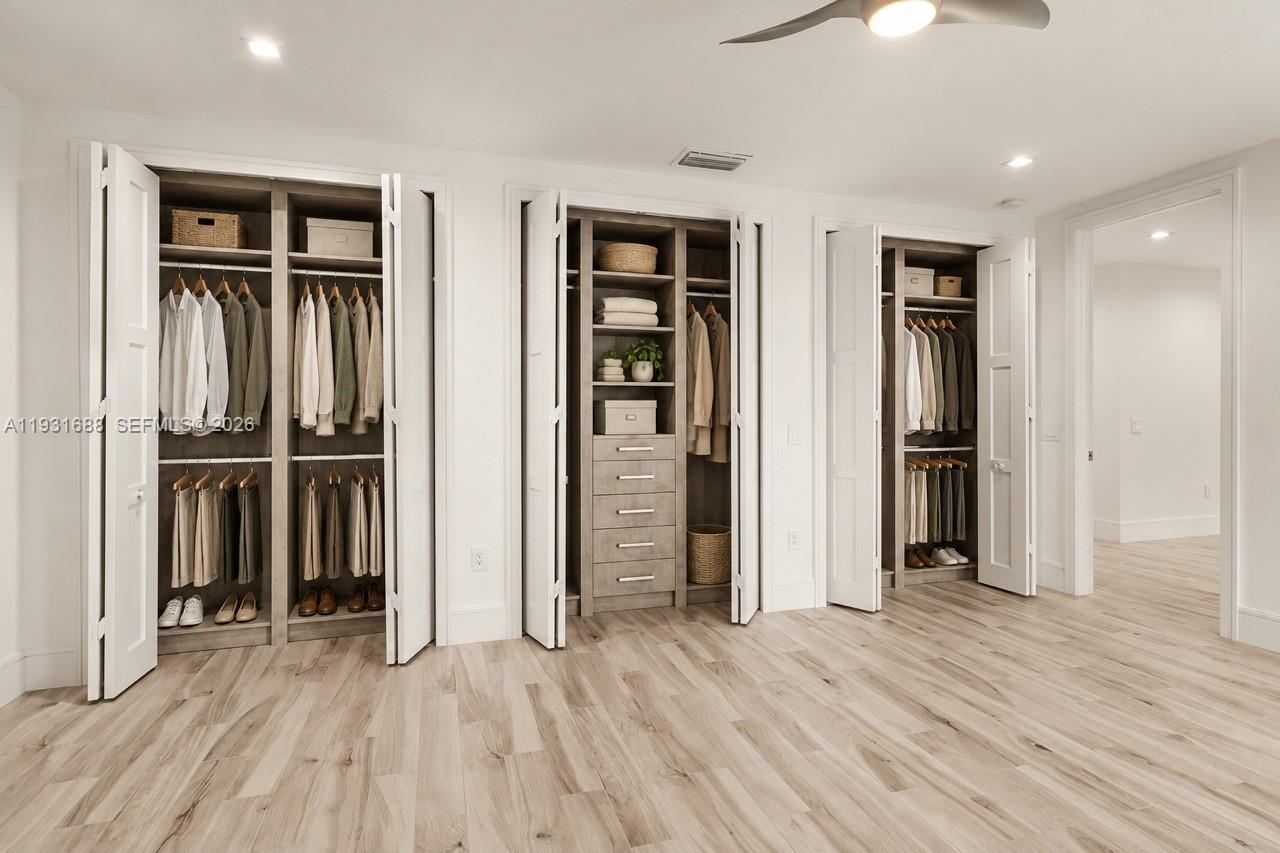 Custom built-in closet system featuring multi-tiered hanging rods, open shelving, integrated drawers with horizontal pulls, and bifold doors set against wood-finish flooring