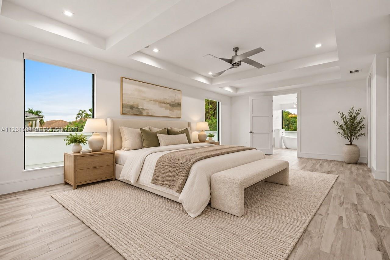 Tray ceiling with recessed lighting, wood-finish flooring, and ceiling fan