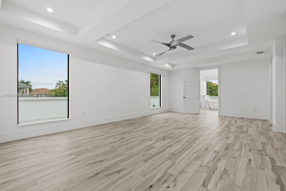 Tray ceiling with recessed lighting, wood-finish flooring, and a modern ceiling fan