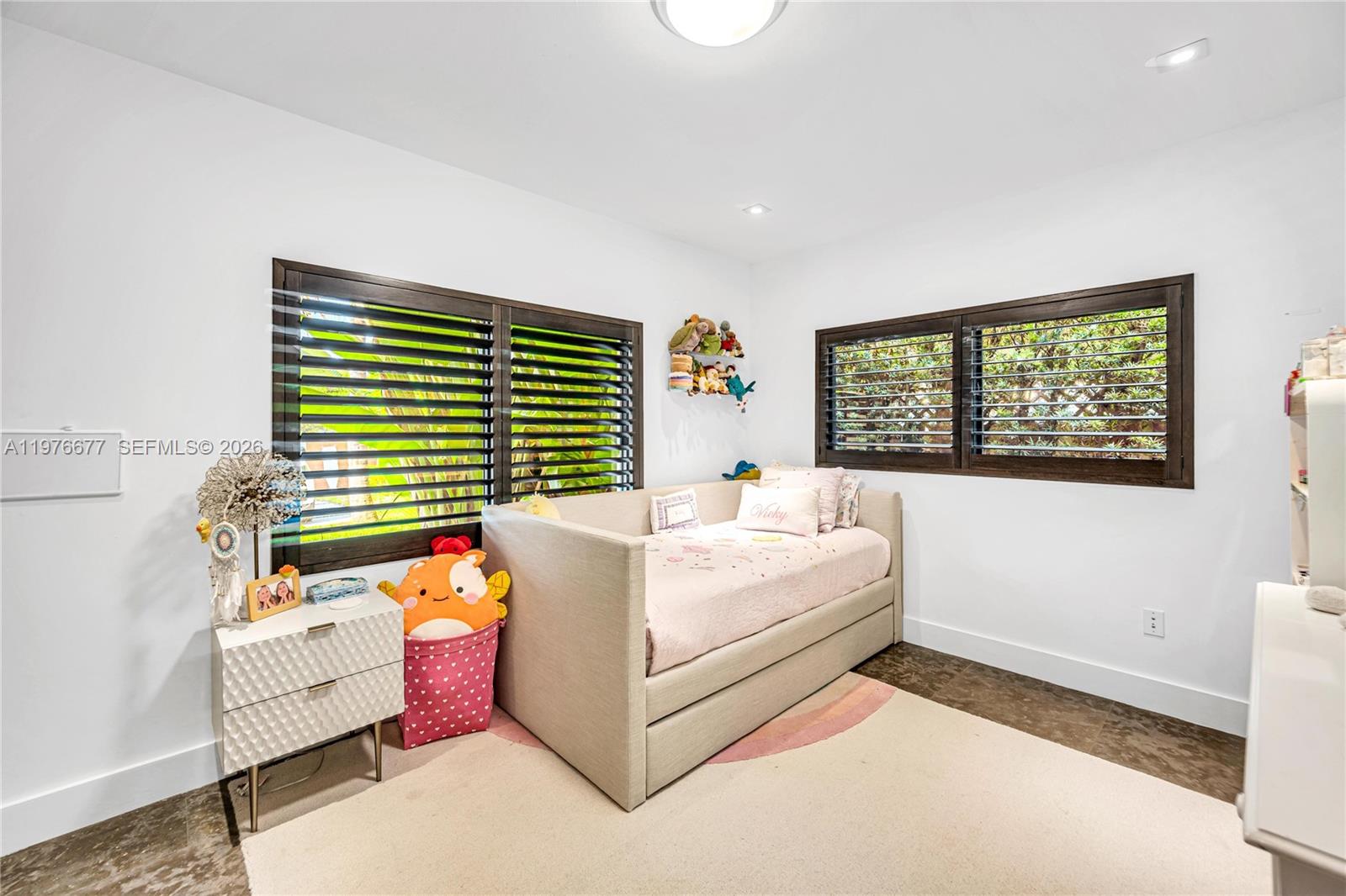 Room featuring dark wood-finish flooring, white walls, recessed ceiling lighting, and large windows with dark wood shutters