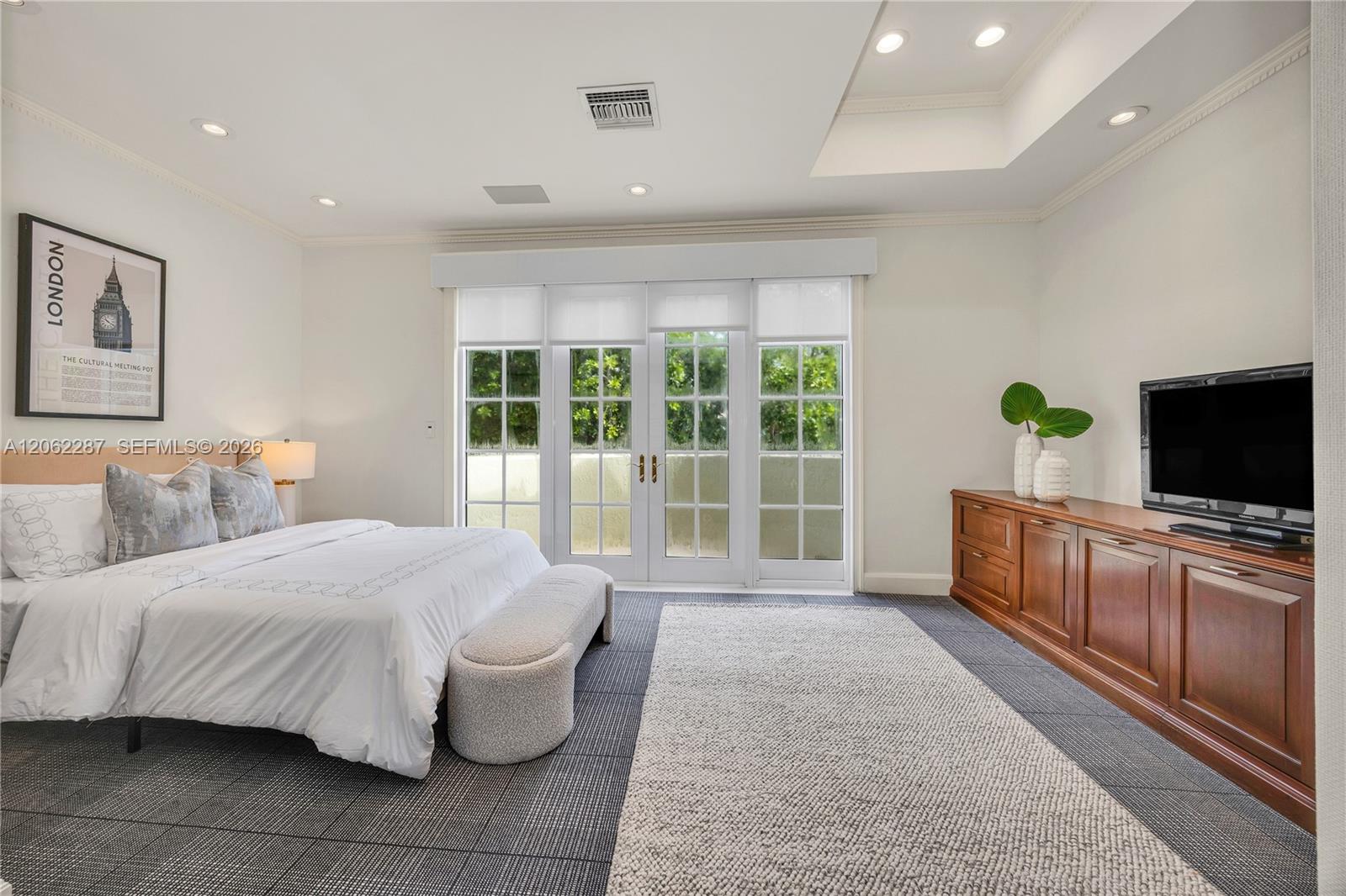 Spacious room featuring a recessed ceiling, grid-patterned glass French doors, built-in wooden cabinetry, recessed lighting, and patterned flooring