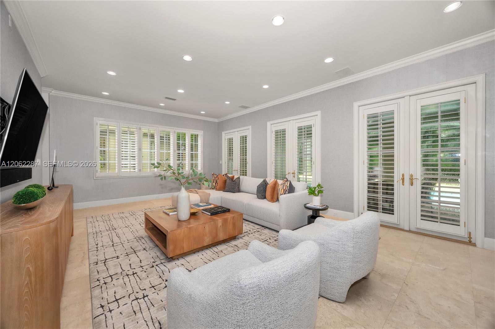 Living area featuring stone flooring, recessed lighting, crown molding, double French doors, and shutter-style window coverings