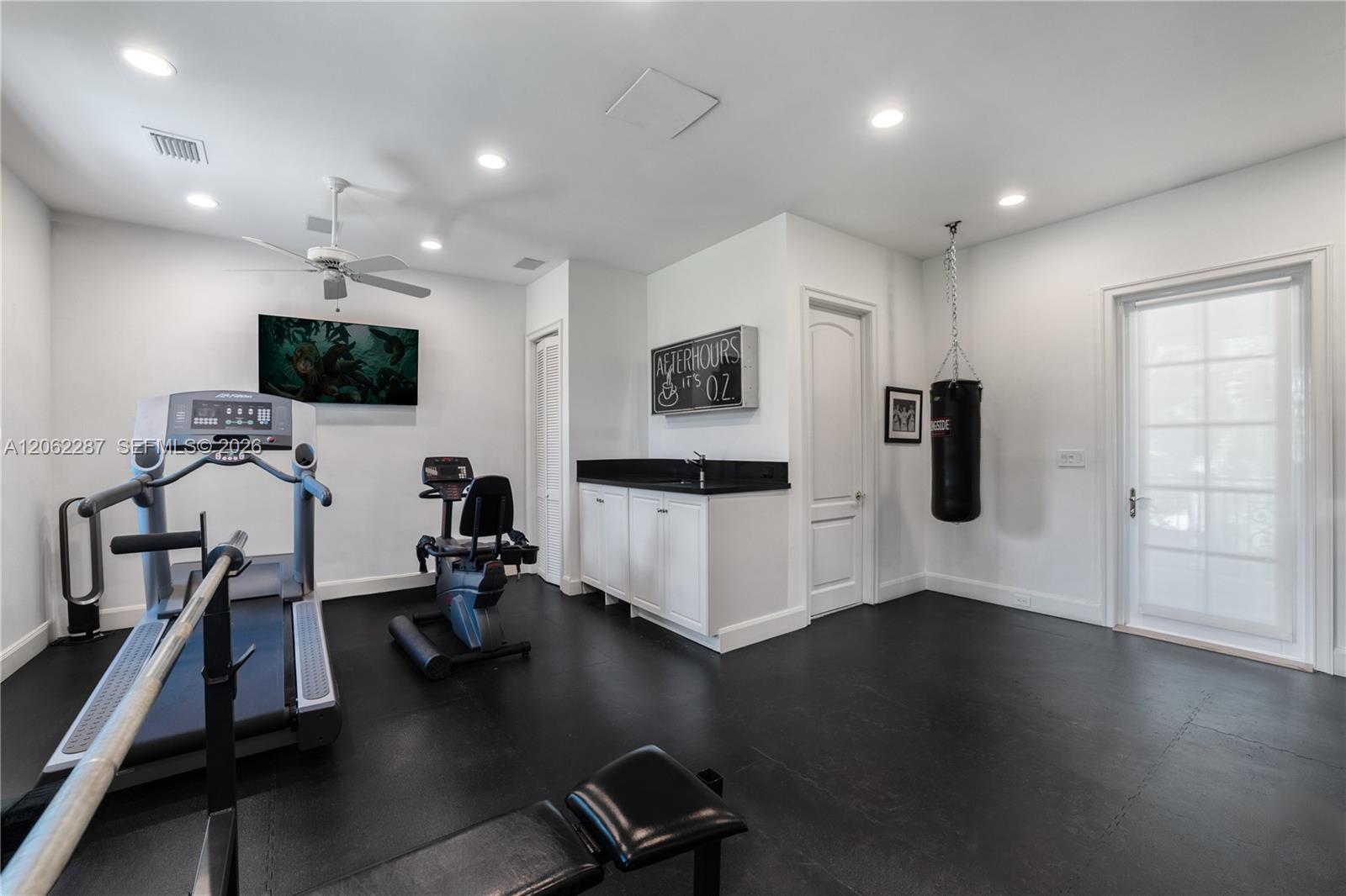Interior space featuring recessed lighting, a ceiling fan, matte-finish flooring, built-in cabinetry with a stone countertop, and a glass-paneled exterior door