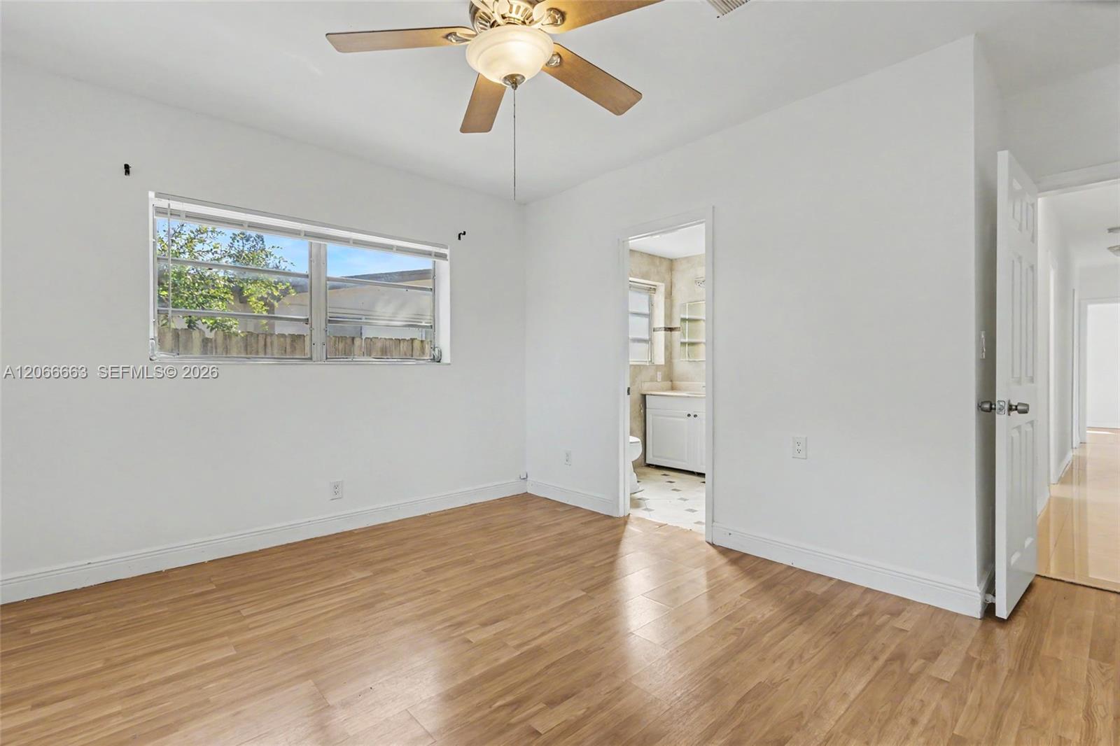 Neutral-toned room featuring wood-finish flooring, a ceiling fan with integrated light fixture, and horizontal sliding windows