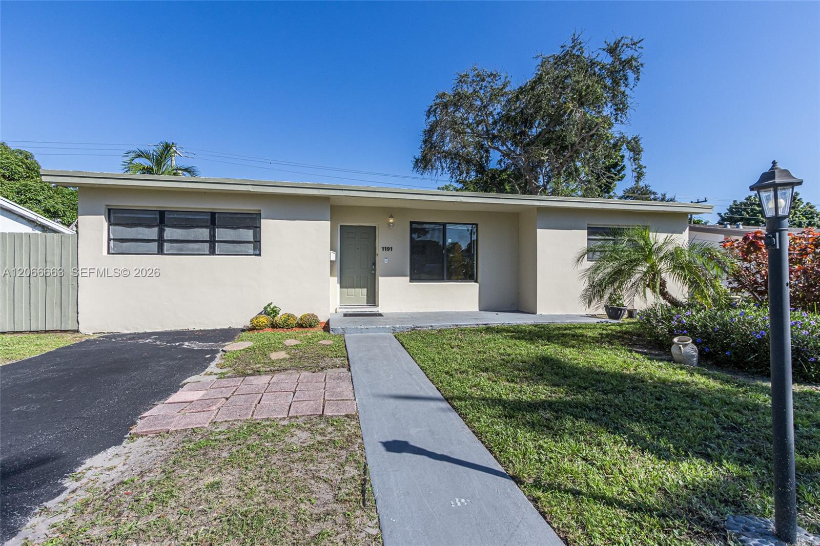 Single-story exterior featuring a low-pitched roof, smooth stucco finish, asphalt driveway, and a concrete walkway