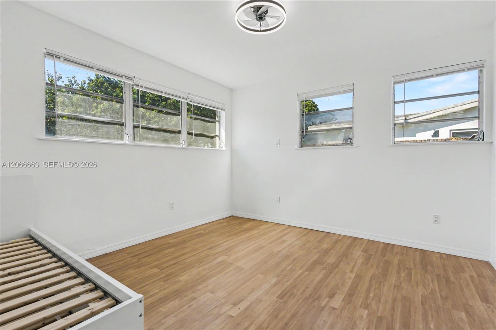 Bright interior featuring wood-finish flooring, multi-pane casement windows, and a modern circular ceiling fan with integrated lighting
