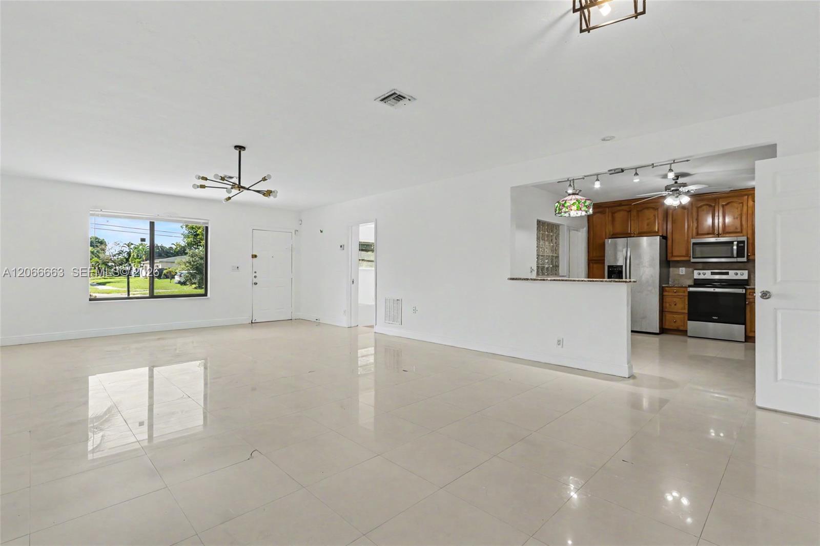 Open-concept interior featuring large-format tile flooring, recessed lighting, a breakfast bar, and kitchen cabinetry with stainless steel appliances
